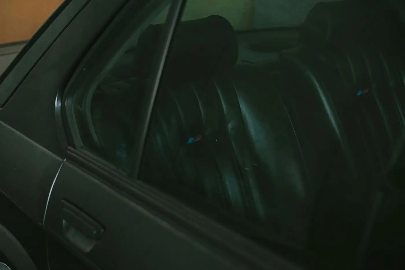 Dark leather car seats seen through a tinted window