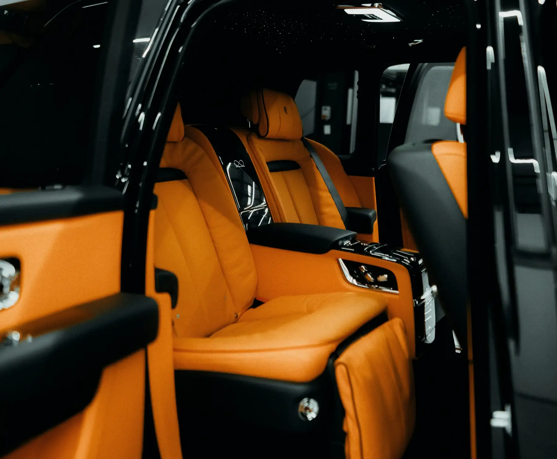 Black Rolls-Royce Cullinan with its rear coach door open onto a tan leather cabin