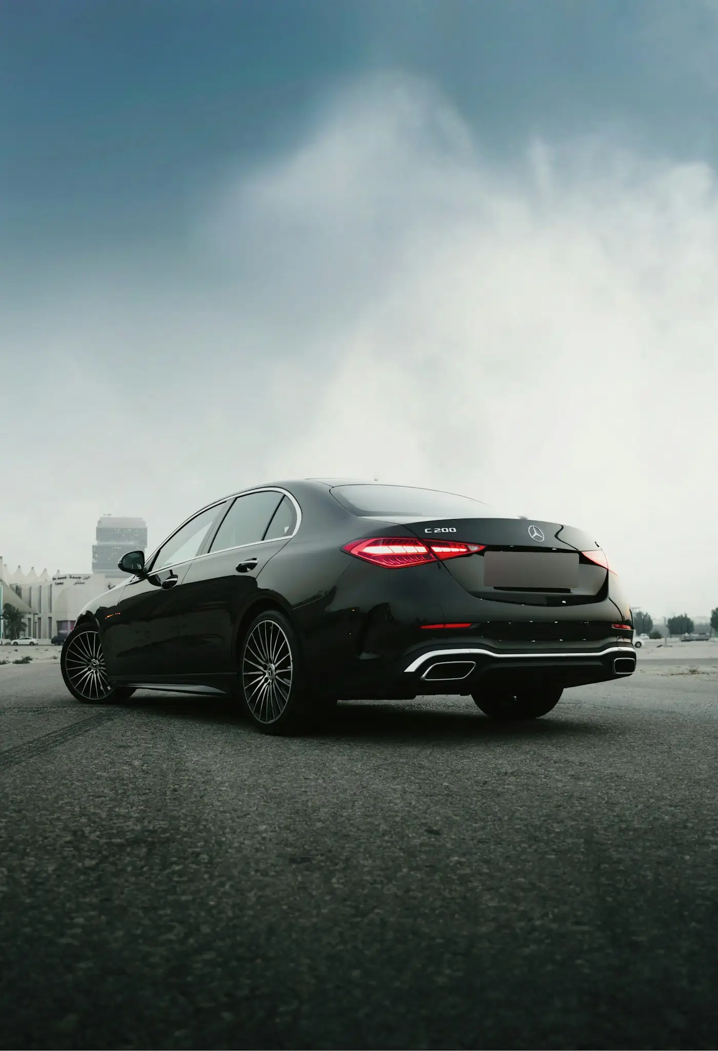 Black Mercedes-Benz sedan under a cloudy, misty sky