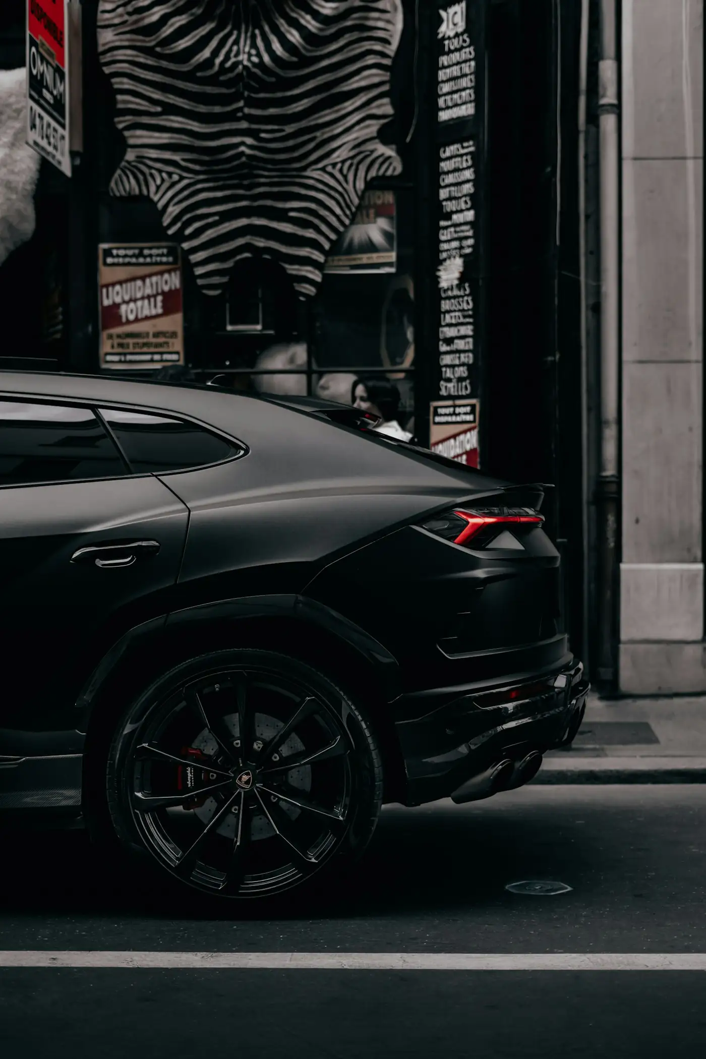 Black Lamborghini Urus side profile on a dark city street