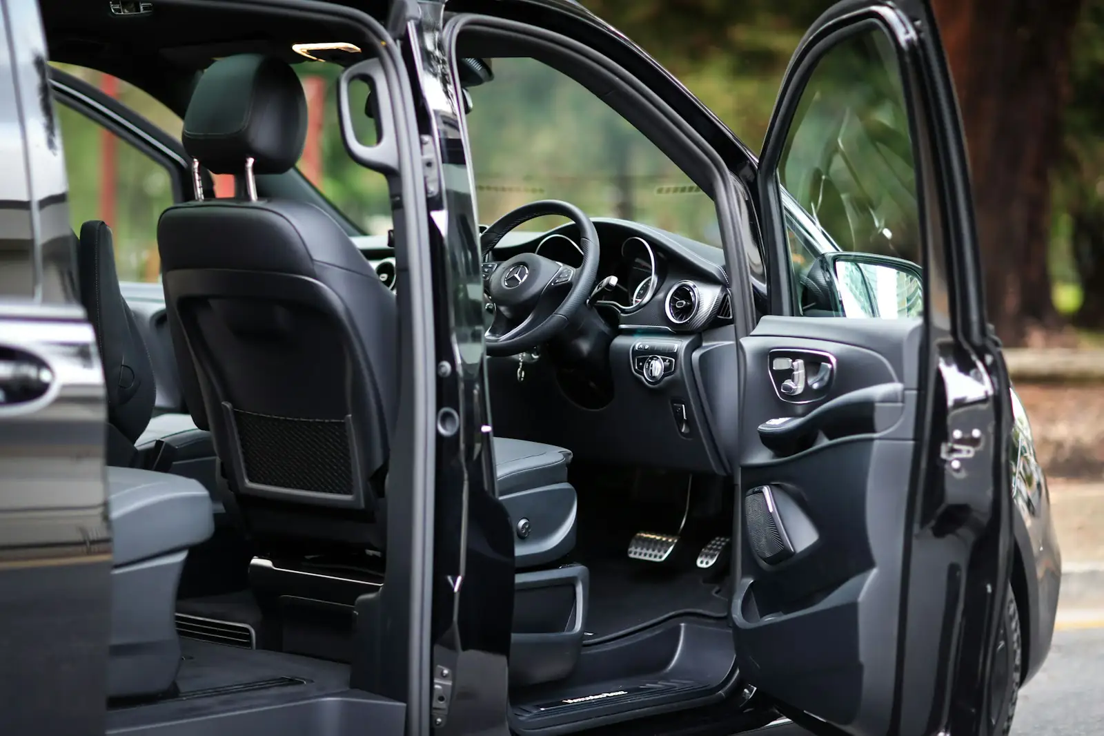 Open side door of a black executive van showing leather seats