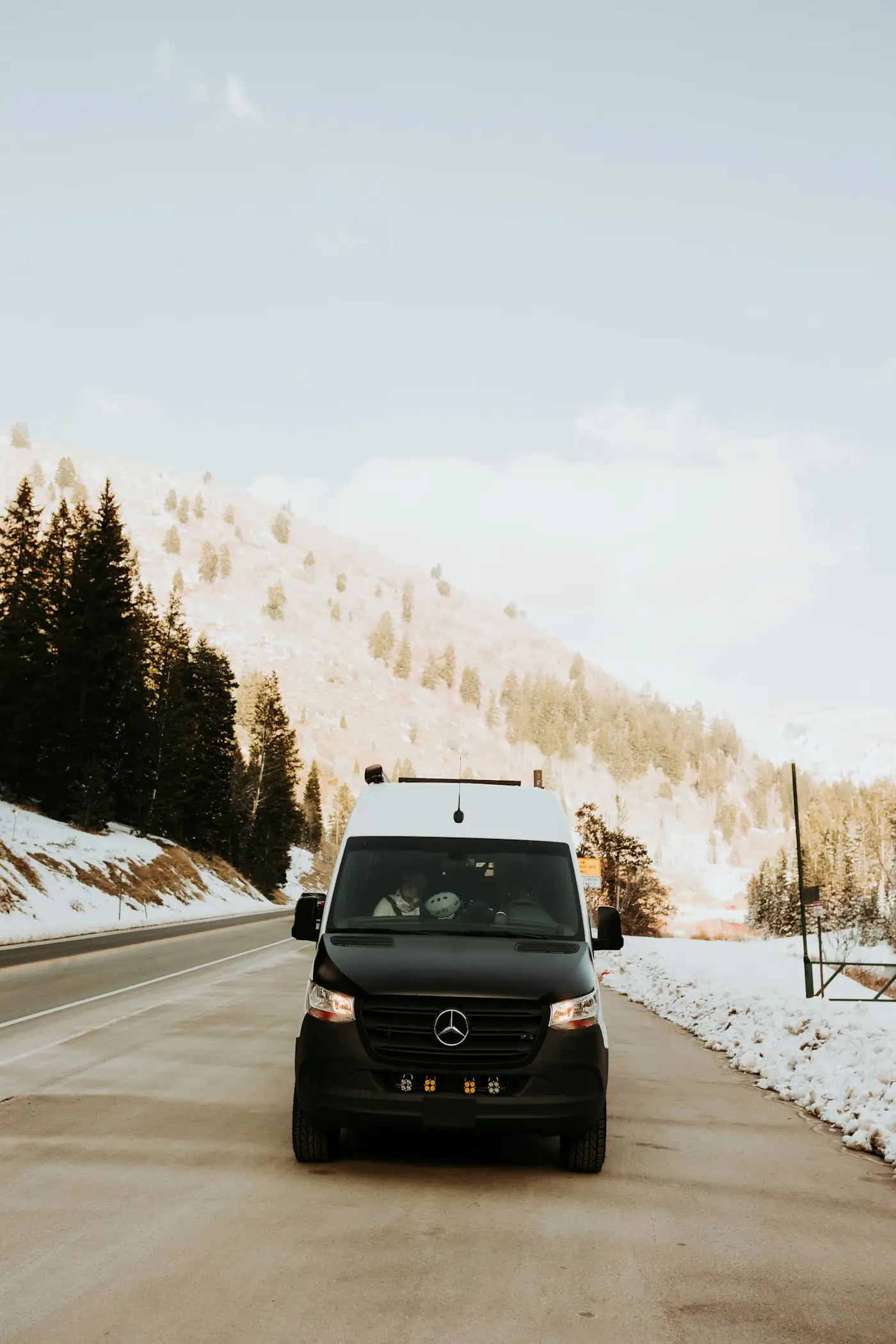 Black Mercedes-Benz Sprinter van driving on a snowy mountain road