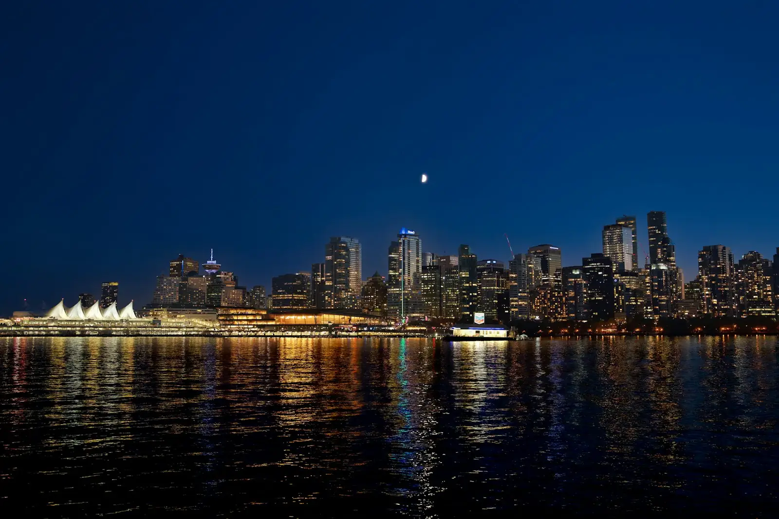 Vancouver skyline at night with the white sails of Canada Place reflected in the harbour